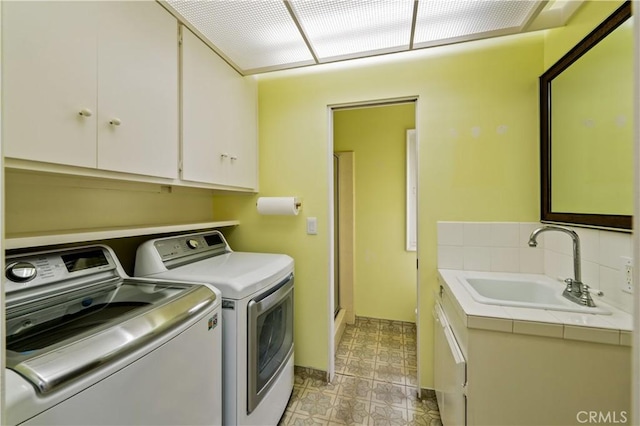 clothes washing area with cabinet space, washing machine and dryer, and a sink