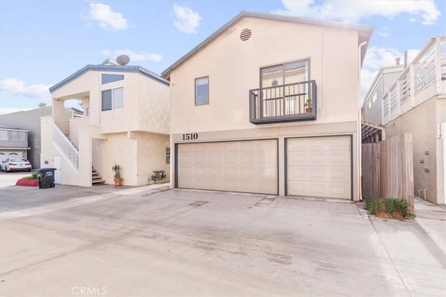 view of front of home with stairs, concrete driveway, an attached garage, and stucco siding