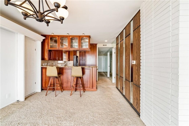 kitchen featuring light carpet, stainless steel refrigerator with ice dispenser, glass insert cabinets, and brown cabinets