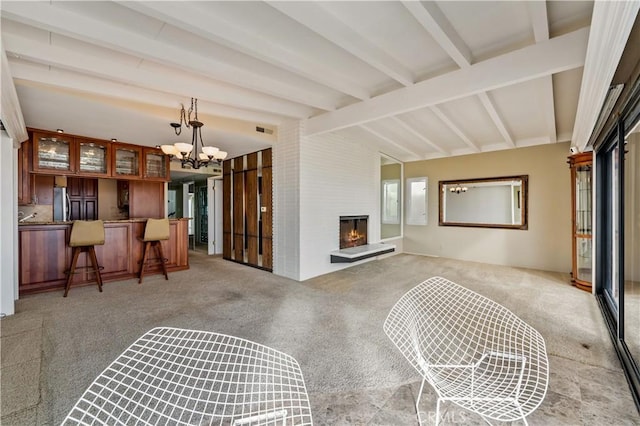 living room featuring vaulted ceiling with beams, light colored carpet, a large fireplace, a notable chandelier, and visible vents