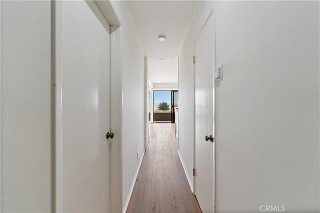 hallway with light wood-style flooring and baseboards