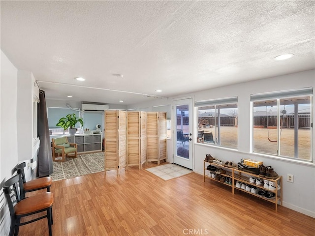 living room featuring a textured ceiling, light hardwood / wood-style flooring, and a wall mounted air conditioner