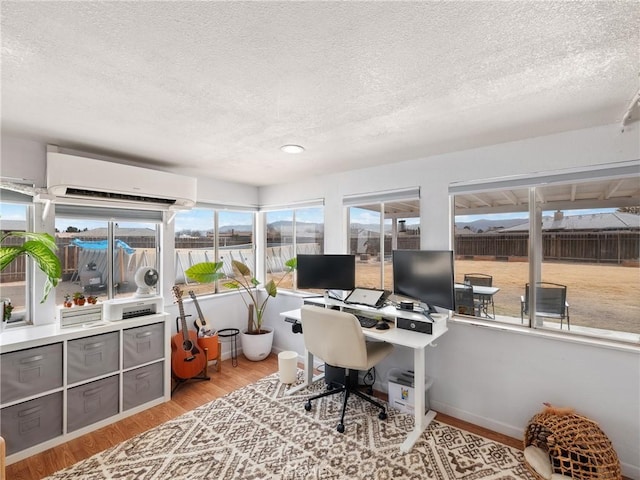 office featuring light wood-type flooring, a wall mounted AC, and a textured ceiling