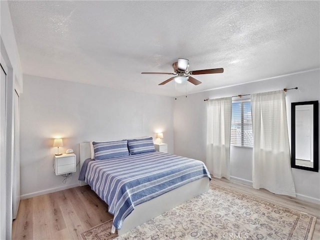 bedroom featuring ceiling fan, light hardwood / wood-style floors, and a textured ceiling