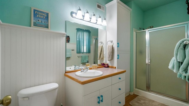 bathroom with a shower with shower door, hardwood / wood-style flooring, toilet, and vanity