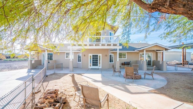 back of house with a balcony, a fire pit, and a patio