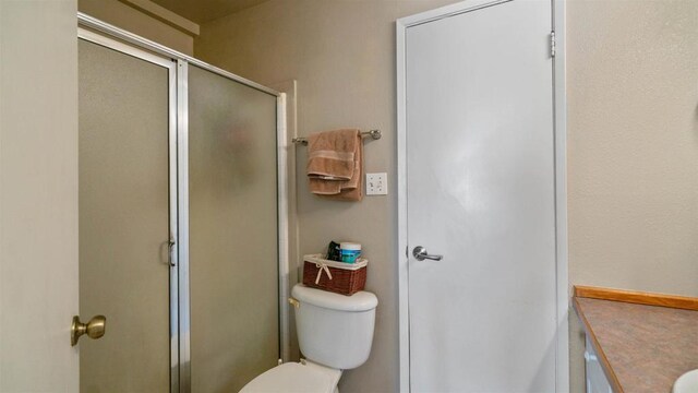 bathroom featuring an enclosed shower, vanity, and toilet