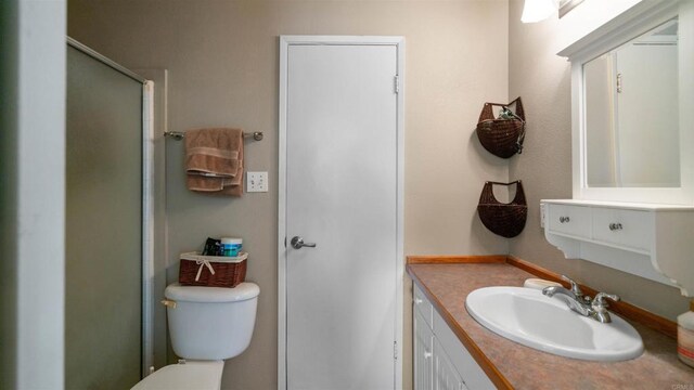 bathroom with a shower with shower door, vanity, and toilet