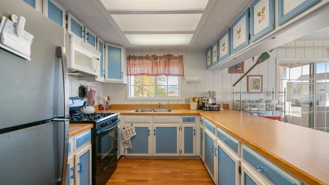 2564 Walters Camp Rd, Winterhaven, CA 92283 - kitchen featuring freestanding refrigerator, white microwave, black range with gas cooktop, light wood-style flooring, and light countertops