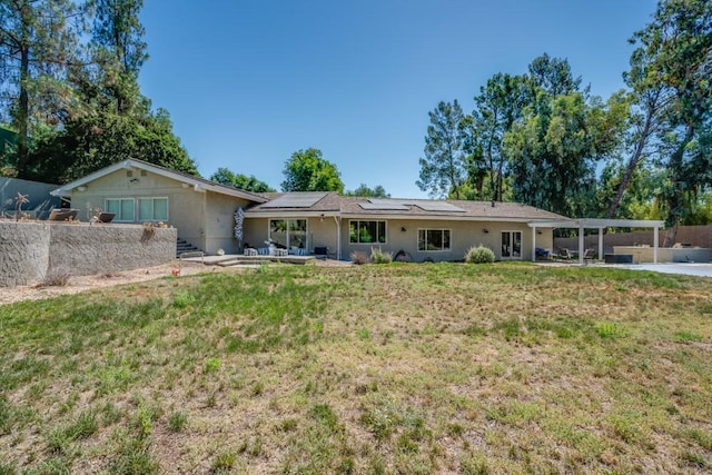 back of property with a yard and solar panels