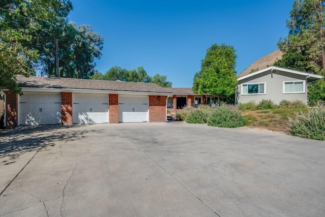 single story home featuring a garage, brick siding, and driveway