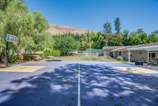 view of basketball court with a mountain view and a trampoline