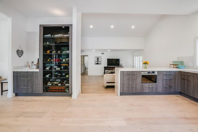 kitchen featuring light wood finished floors, modern cabinets, open floor plan, a peninsula, and light countertops