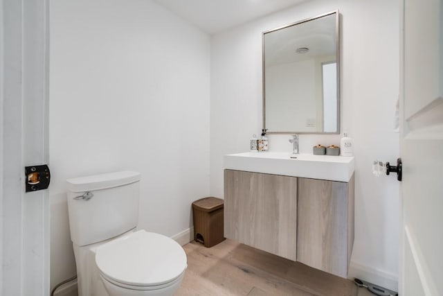 bathroom with wood-type flooring, toilet, and vanity