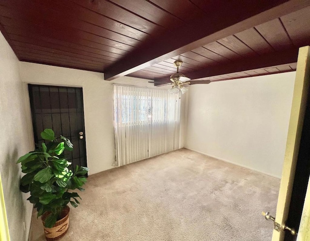 carpeted spare room featuring ceiling fan, wood ceiling, and beamed ceiling