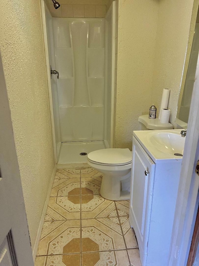 bathroom with walk in shower, vanity, toilet, and tile patterned flooring