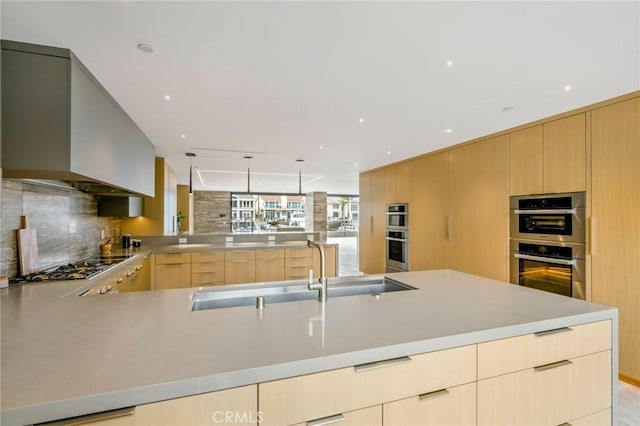 kitchen with decorative backsplash, sink, appliances with stainless steel finishes, light brown cabinetry, and wall chimney exhaust hood