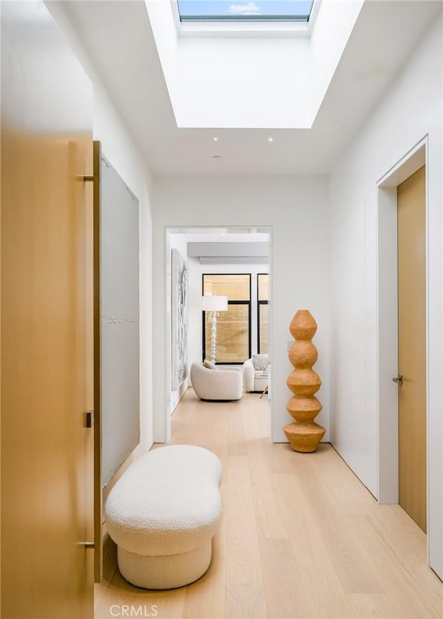 hall with hardwood / wood-style flooring and a skylight