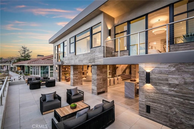 patio terrace at dusk with an outdoor living space with a fireplace