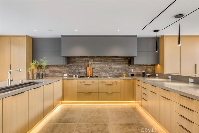 kitchen featuring light brown cabinets, wall chimney range hood, decorative backsplash, sink, and gas stovetop