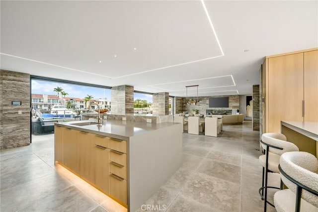433 Harbor Island Dr, Newport Beach, CA 92660 - kitchen with modern cabinets, open floor plan, light brown cabinetry, a center island with sink, and a wall of windows