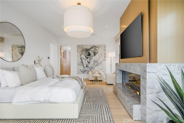 bedroom with light hardwood / wood-style floors and a premium fireplace