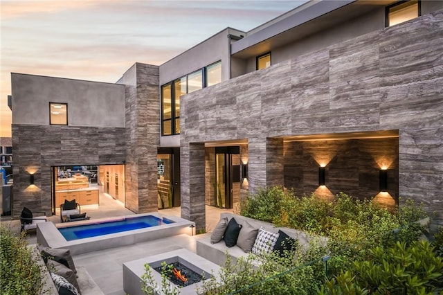 back house at dusk with a patio and an outdoor living space with a fire pit