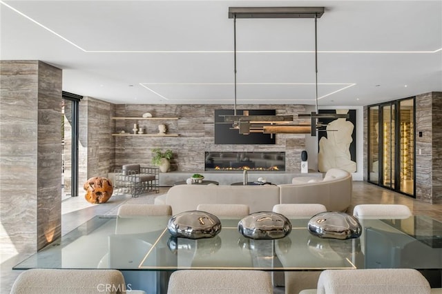 dining area with expansive windows, a fireplace, and wooden walls