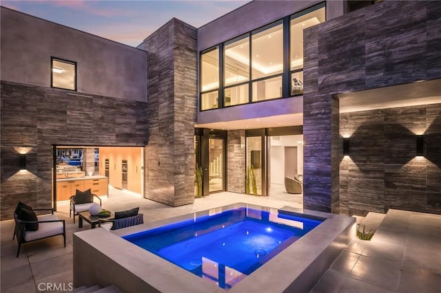 433 Harbor Island Dr, Newport Beach, CA 92660 - back of property at dusk featuring an in-ground hot tub, area for grilling, a patio area, and stone siding