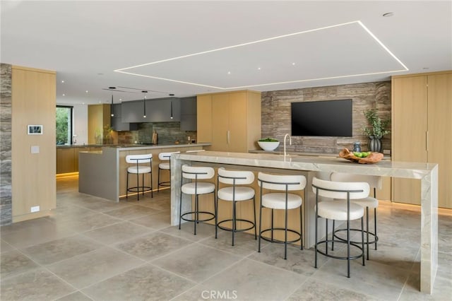 kitchen featuring tasteful backsplash, gray cabinetry, a breakfast bar area, and a large island