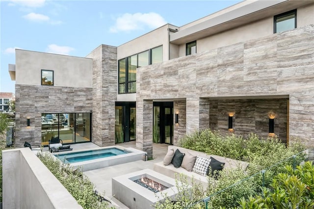 rear view of house featuring an outdoor living space with a fire pit, an in ground hot tub, and a patio