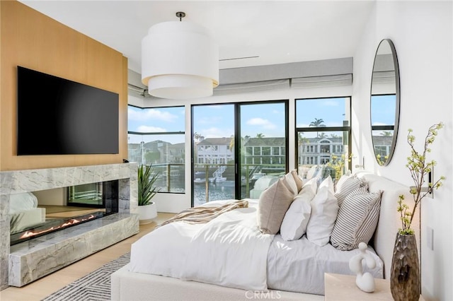 bedroom with access to exterior, a fireplace, multiple windows, and hardwood / wood-style flooring