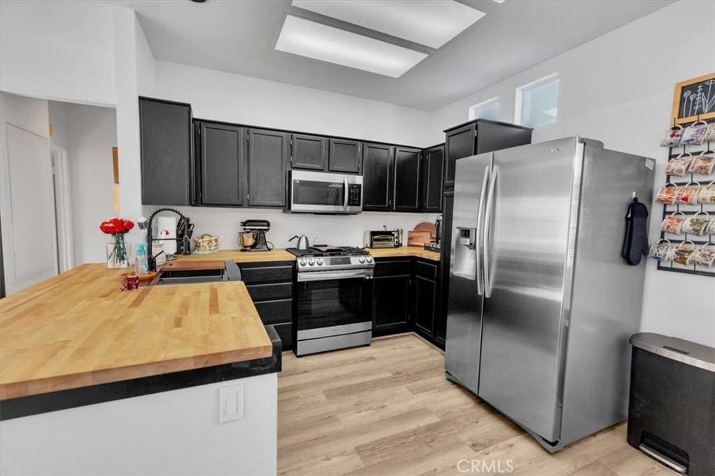 kitchen featuring wood counters, appliances with stainless steel finishes, light hardwood / wood-style flooring, and sink