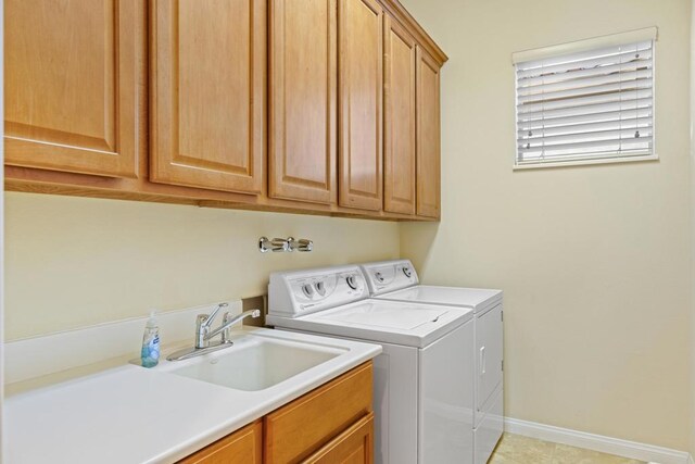 washroom with light tile patterned floors, sink, washer and dryer, and cabinets