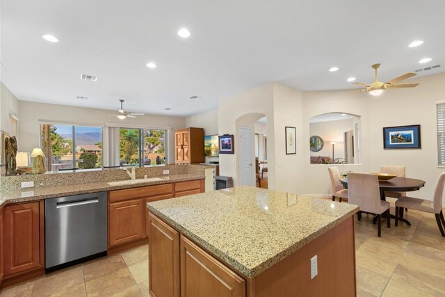 kitchen featuring a kitchen island, ceiling fan, sink, light stone counters, and stainless steel dishwasher