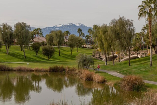 view of property's community with a water and mountain view and a lawn