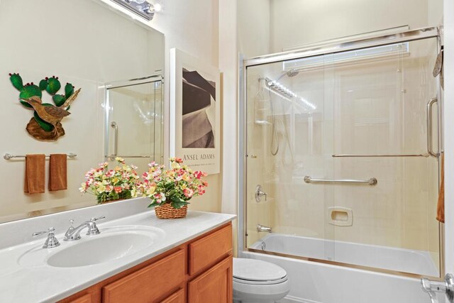 full bathroom with enclosed tub / shower combo, vanity, and toilet