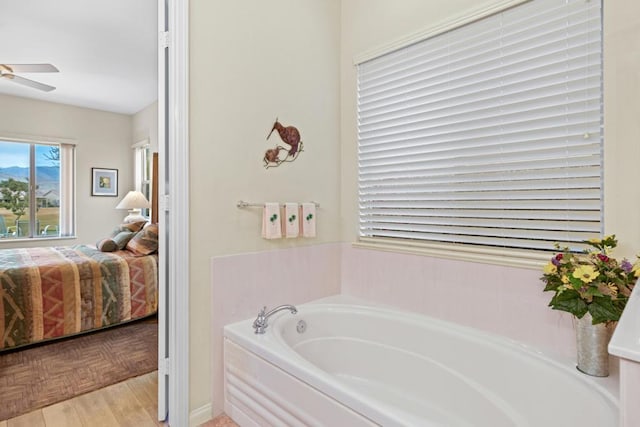 bathroom with ceiling fan, a washtub, and wood-type flooring