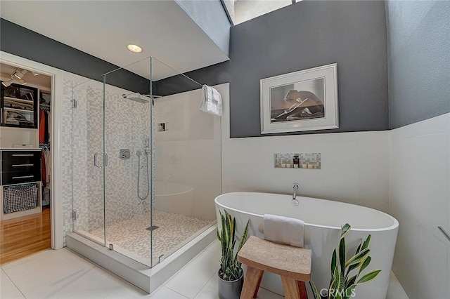 bathroom with tile patterned floors, separate shower and tub, and tile walls