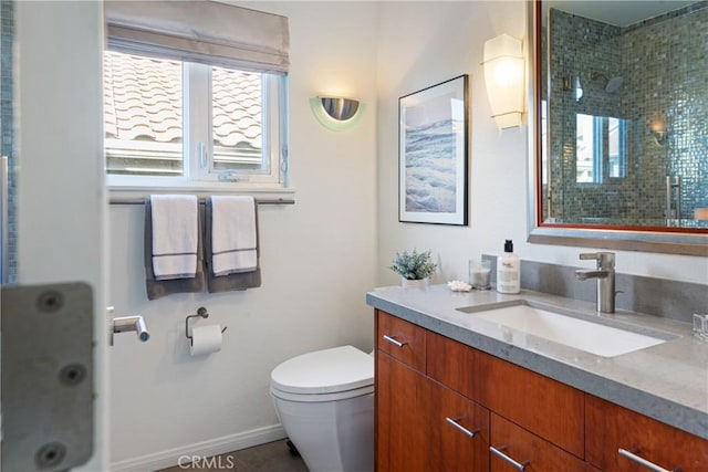 bathroom featuring tiled shower, vanity, and toilet