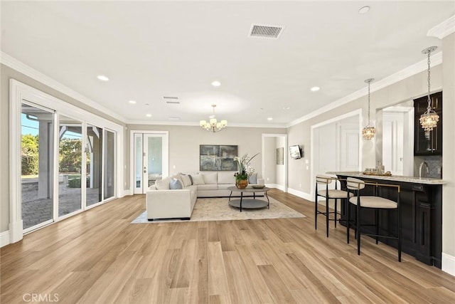 living room with sink, an inviting chandelier, crown molding, and light wood-type flooring