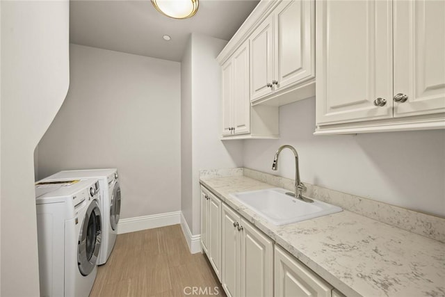 laundry room featuring cabinets, light hardwood / wood-style floors, independent washer and dryer, and sink