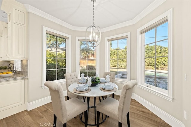 dining space featuring light wood-type flooring, a notable chandelier, sink, and crown molding