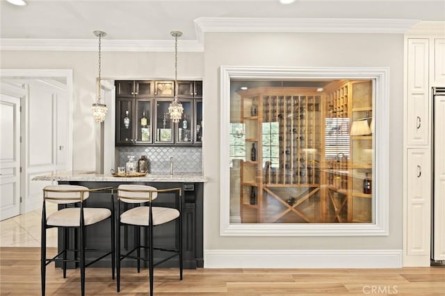 bar featuring backsplash, light wood-type flooring, hanging light fixtures, crown molding, and light stone counters