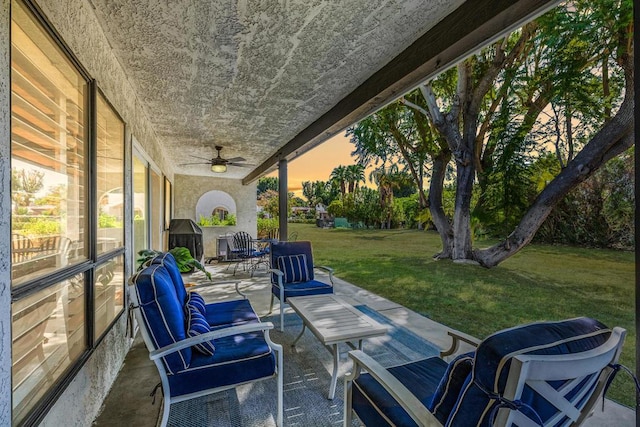 patio terrace at dusk featuring a lawn and ceiling fan