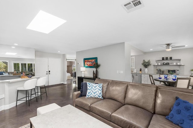 living room featuring a fireplace, a skylight, and ceiling fan