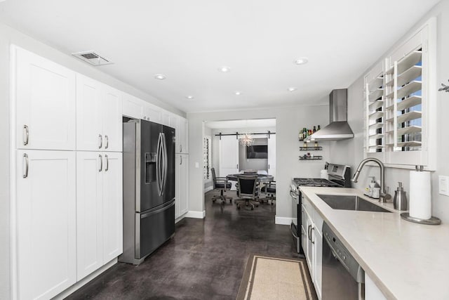 kitchen featuring white cabinetry, wall chimney range hood, sink, and appliances with stainless steel finishes