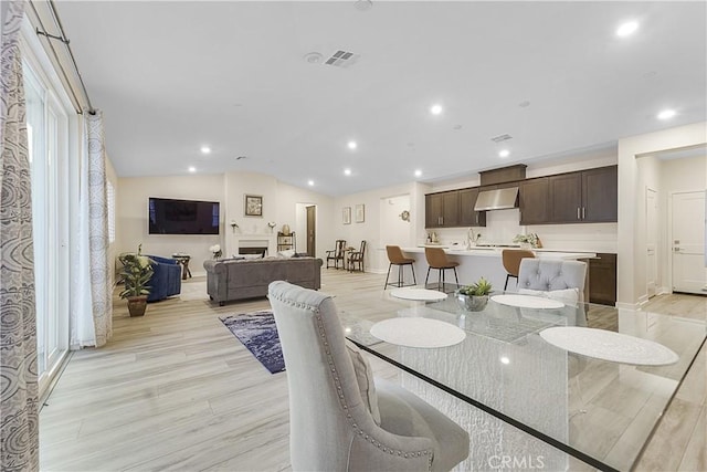 dining space featuring lofted ceiling and light wood-type flooring