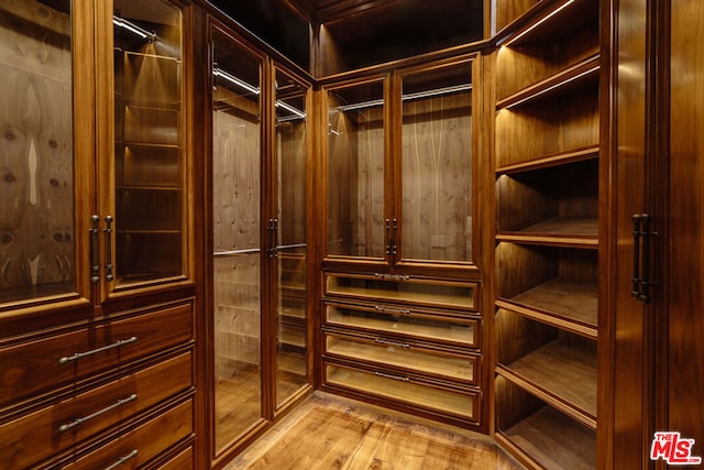 walk in closet with light hardwood / wood-style floors