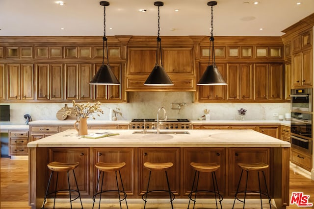 kitchen with a kitchen bar, backsplash, and a kitchen island with sink